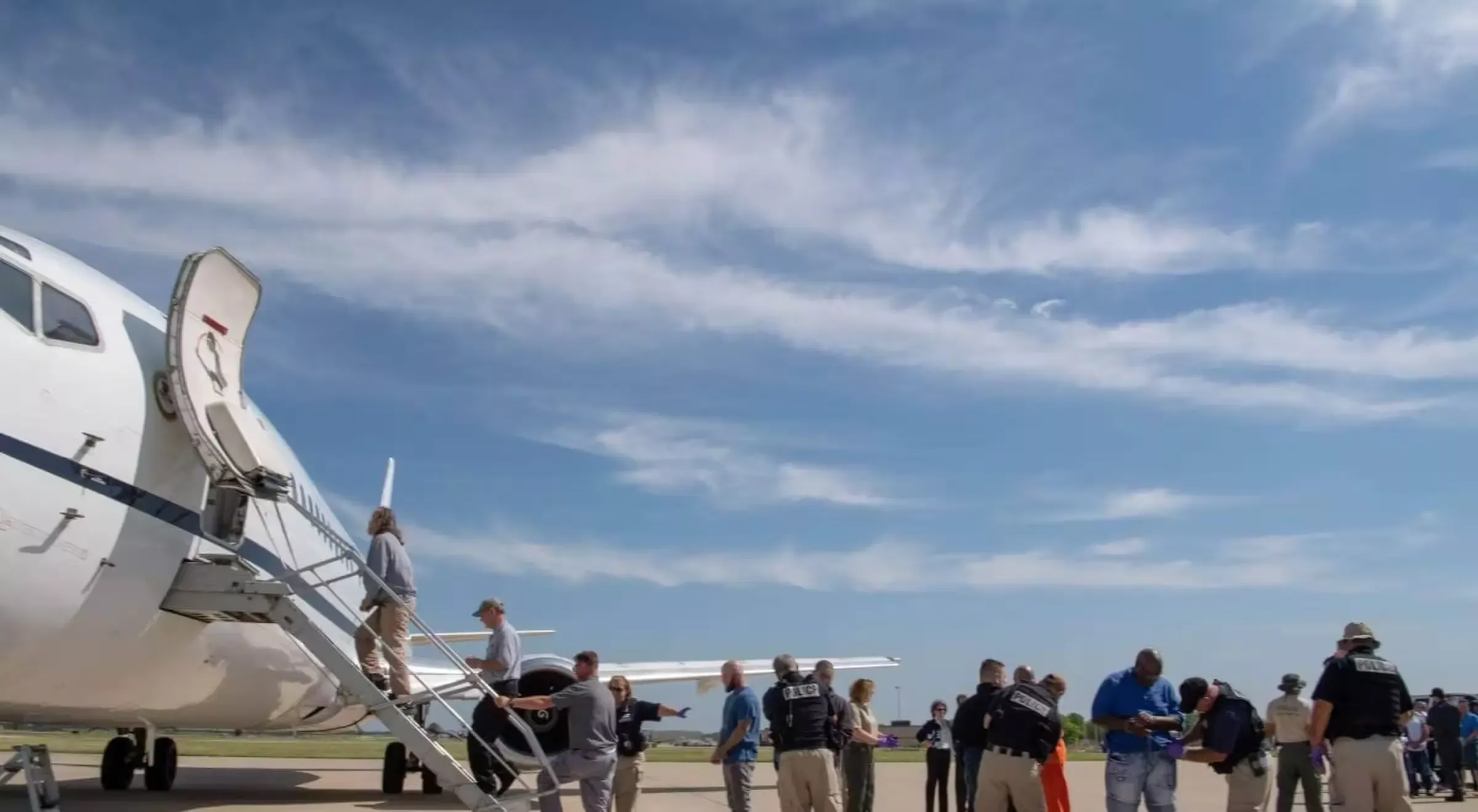 A plane with police and prisoners getting on